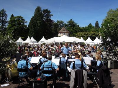 Dirigent Andrej Baumgard aus Orchestersicht, Publikum und Schloßpark im Hintergrund