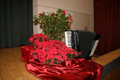 Bühnendekoration mit roten Rosen, rotem Tuch und Akkordeon